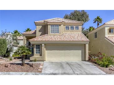 Tan two-story home featuring a terracotta-colored roof, two-car garage, and desert landscaping at 1833 Winners Cup Dr, Las Vegas, NV 89117