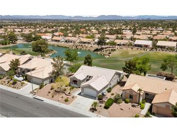 Beautiful aerial view of a well-maintained community with lush landscaping, pond, and golf course in the background at 2816 High Range Dr, Las Vegas, NV 89134