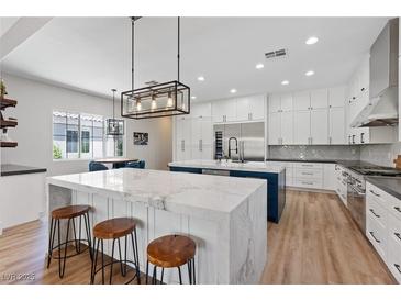 Bright, modern kitchen with large marble island, stainless appliances, and custom white cabinetry at 7289 Sea Anchor Ct, Las Vegas, NV 89131