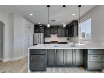 Modern kitchen features dark cabinetry, stainless steel appliances, and a large island with white countertops at 8108 Artistic Heights Ct, Las Vegas, NV 89143