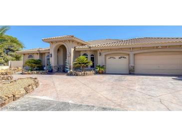 Stunning home features a tile roof, archway entrance, and three-car garage, surrounded by desert landscaping at 4011 Scott Russell Ct, North Las Vegas, NV 89031