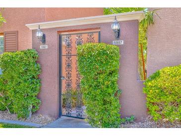 Inviting courtyard entrance with secure gate and well-manicured hedges for added privacy at 10667 Olympic Pine Dr, Las Vegas, NV 89135