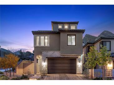 Contemporary two-story home featuring stone accents and a two-car garage, beautifully illuminated at twilight at 2367 Ridgeline Wash St, Las Vegas, NV 89138