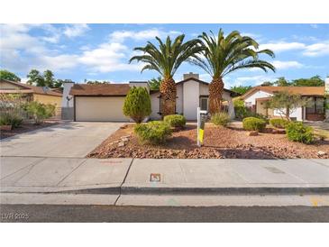 Charming single-story home featuring a two-car garage, mature palm trees, and desert landscaping at 4016 Stormcrest Dr, Las Vegas, NV 89107