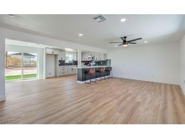 Bright, open-concept living room featuring a modern kitchen with a bar and wood-look flooring at 5200 Blanton Dr, Las Vegas, NV 89122