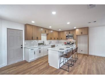 Bright kitchen features stainless steel appliances, an island with seating, and white countertops at 5279 Consul Ave, Las Vegas, NV 89142