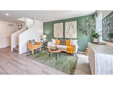 Inviting living room featuring green accent wall, neutral furniture, stylish decor, and luxury vinyl plank flooring at 7351 Kyle Cove Dr # Lot 208, North Las Vegas, NV 89084
