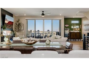 An open living room with modern furnishings and a sliding glass door to a balcony with a view at 2151 Noble Perch St, Las Vegas, NV 89138