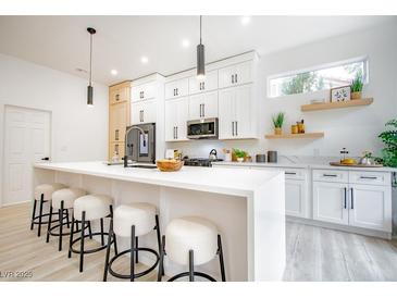 Modern kitchen with a large island, white cabinets, stainless steel appliances, and stylish pendant lighting at 2561 Terrytown Ave, Henderson, NV 89052