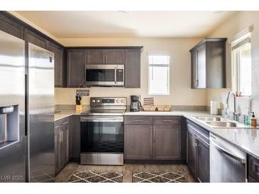 Modern kitchen featuring stainless steel appliances, dark cabinets, and granite countertops at 2629 Mocha Pearl Ct, North Las Vegas, NV 89086