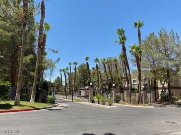 View of the Spanish Palms gated community entrance lined with mature trees and landscaping at 5250 S Rainbow Blvd # 1010, Las Vegas, NV 89118