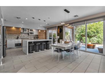 Bright, modern kitchen featuring an island with seating and stainless steel appliances, with easy access to outdoor patio at 556 Caribbean Palm Dr, Las Vegas, NV 89138