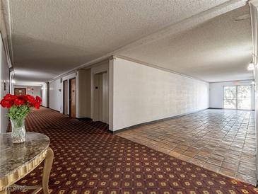 Condo hallway with patterned carpet and tile and an exit leading outside at 725 N Royal Crest Cir # 228, Las Vegas, NV 89169