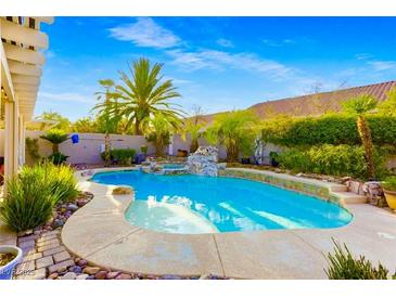 Backyard pool featuring a rock waterfall surrounded by mature landscaping at 8928 Rusty Rifle Ave, Las Vegas, NV 89143