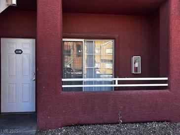 Exterior view of a unit with a white front door, a red frame, and a window reflecting the complex at 4730 E Craig Rd # 1148, Las Vegas, NV 89115