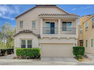 Two-story home with a tan stucco exterior, a balcony, and a two-car garage at 8307 Fort Hallock Ave, Las Vegas, NV 89131