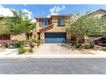 Beautiful two-story home with a blue garage door, landscaped front yard, and a brick driveway at 10086 Adina Ct, Las Vegas, NV 89141