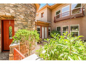 Inviting stone facade entrance with a red door and lush landscaping adds curb appeal to the property at 1737 Cypress Manor Dr, Henderson, NV 89012