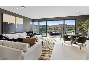Bright living room featuring modern furnishings, artwork, and expansive sliding doors to a patio with mountain views at 40 Heron Harbour Dr, Henderson, NV 89011