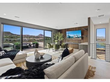 Open-concept living room with modern furniture, a dining area, and a large sliding glass door with mountain views at 40 Heron Harbour Dr, Henderson, NV 89011
