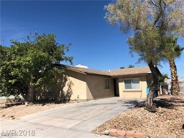 A cozy single-story home featuring a neutral exterior, xeriscaped landscaping, and mature trees at 6196 W University Ave, Las Vegas, NV 89103