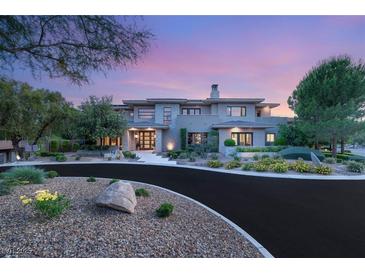 A luxurious multi-story home boasting an expertly landscaped yard and winding driveway at sunset at 11 Misty Peaks Ct, Las Vegas, NV 89135