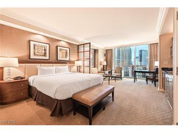 Bright bedroom with a comfortable king bed, seating area, and floor to ceiling windows at 145 E Harmon Ave # 919, Las Vegas, NV 89109