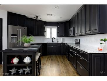 Modern kitchen with black cabinets, stainless steel appliances, and an island with seating, offers a stylish and functional space at 414 Crystal Canyon Dr, Mesquite, NV 89027