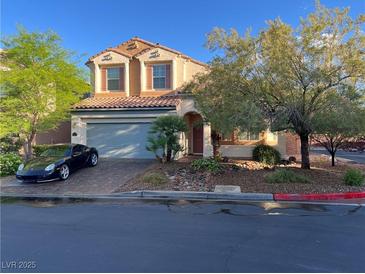 Charming two-story home with a tile roof, arched entryway, and a well-manicured front yard with mature trees at 11625 Cabo Del Verde Ave, Las Vegas, NV 89138