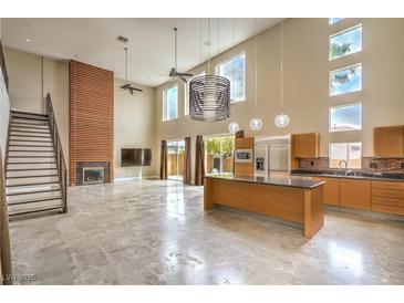 Bright living room featuring a fireplace, modern kitchen, and high ceilings at 1448 Canyon Ledge Ct, Las Vegas, NV 89117