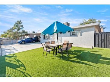 Backyard featuring a dining set with a blue umbrella on an artificial lawn at 5004 Cannon Blvd, Las Vegas, NV 89108