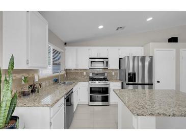 Bright kitchen with white cabinets, granite countertops, stainless steel appliances, and tile flooring at 509 Regal Robin Way, North Las Vegas, NV 89084