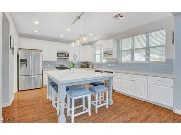 Bright kitchen features stainless appliances, a central island with seating, and wooden floor at 5642 Breckenridge St, North Las Vegas, NV 89081