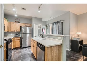 This kitchen features wood cabinetry, stainless steel appliances, and tiled flooring at 6321 Rolling Rose St # 201, North Las Vegas, NV 89081