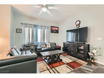 Inviting living room featuring hardwood floors, plush sofas, TV set, ceiling fan, and natural light at 6321 Rolling Rose St # 201, North Las Vegas, NV 89081
