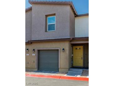 Two-story townhouse featuring a one-car garage, a yellow door, and a simple, modern design at 7977 Whisper Words Ave, Las Vegas, NV 89113