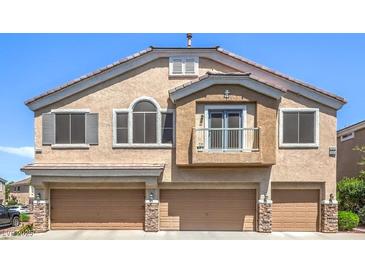 Townhome with a balcony, three garage doors, and a stucco facade at 1554 Ward Frontier Ln, Henderson, NV 89002