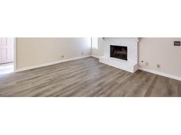 Bright living room with vinyl floors featuring a white painted brick fireplace at 3683 Villa Knolls East Dr, Las Vegas, NV 89120