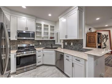 This modern kitchen features white cabinetry, stainless steel appliances, and stylish backsplash at 75 N Valle Verde Dr # 211, Henderson, NV 89074