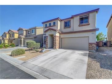 Two-story home featuring a beige exterior, rock accents, attached two-car garage, and well-maintained landscaping at 405 Prairie Moon Ave, North Las Vegas, NV 89084