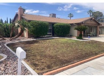 Charming single-story home featuring desert landscaping with a fresh lawn, palm trees, and a brick exterior at 5821 Santa Catalina Ave, Las Vegas, NV 89108