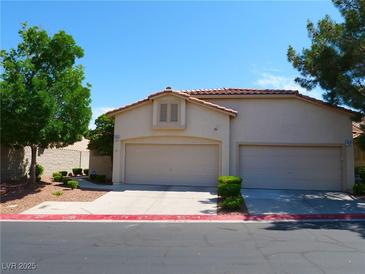 Charming home featuring a two-car garage, red tile roof, and desert-friendly landscaping at 9705 Templemore Ave # 102, Las Vegas, NV 89129