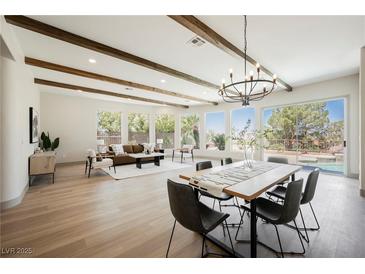 Open living and dining area featuring exposed wood beams, chandelier, and large windows with outdoor views at 2177 Magnolia Pond Ct, Henderson, NV 89052