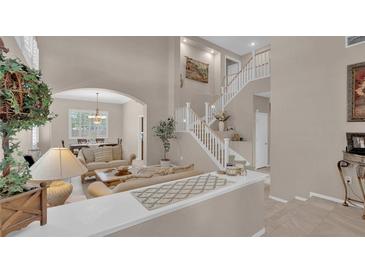 Bright living room featuring elegant staircase and open floor plan to dining area at 9017 Cotton Rose Way, Las Vegas, NV 89134