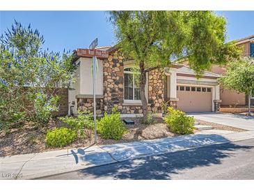 Charming single-story home with stone accents, lush landscaping, and a well-maintained front yard at 10121 Iron Wood Peak Ave, Las Vegas, NV 89166