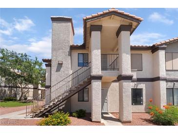 Two-story condo featuring stairs, red gravel landscaping, and tan stucco with dark trim at 1575 W Warm Springs Rd # 2822, Henderson, NV 89014