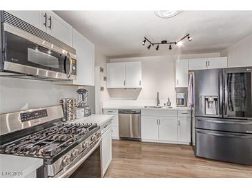 Modern kitchen features stainless steel appliances, gas range, white cabinets, and wood-look floors at 3417 Lillis Cir, North Las Vegas, NV 89030