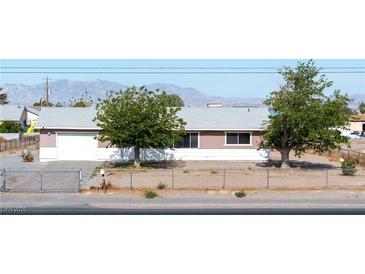 Single story home with a fenced front yard and two mature trees providing shade at 2440 Homestead Rd, Pahrump, NV 89048