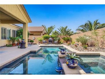 Inviting backyard pool featuring lush landscaping, a charming fire pit, and a serene outdoor living space at 6440 Bristlebird St, North Las Vegas, NV 89084