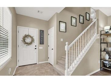Bright entryway featuring a white door with wreath, neutral walls, and staircase leading to the upper level at 6869 Desert Thrasher Dr, North Las Vegas, NV 89084